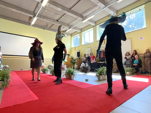 défilé dans une salle sur tapis rouge, trois silhouettes se dessinnent