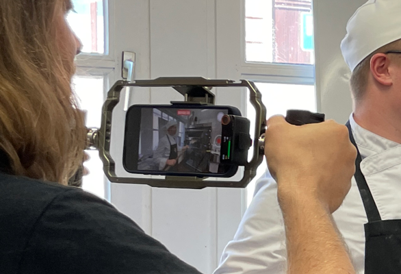 cadreur qui tient sa caméra et film un élève qui montre ce qu'il a appris en boulangerie