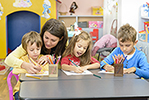 Kids drawing at kindergarten being supervised by educator