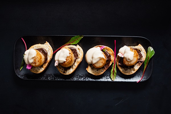  scallop appetizers with sauce on the black background